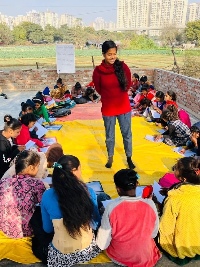 Outdoor Social Emotional Learning workshop with adolescents in Barola JJ slum, Noida, with a facilitator leading a session on a yellow mat